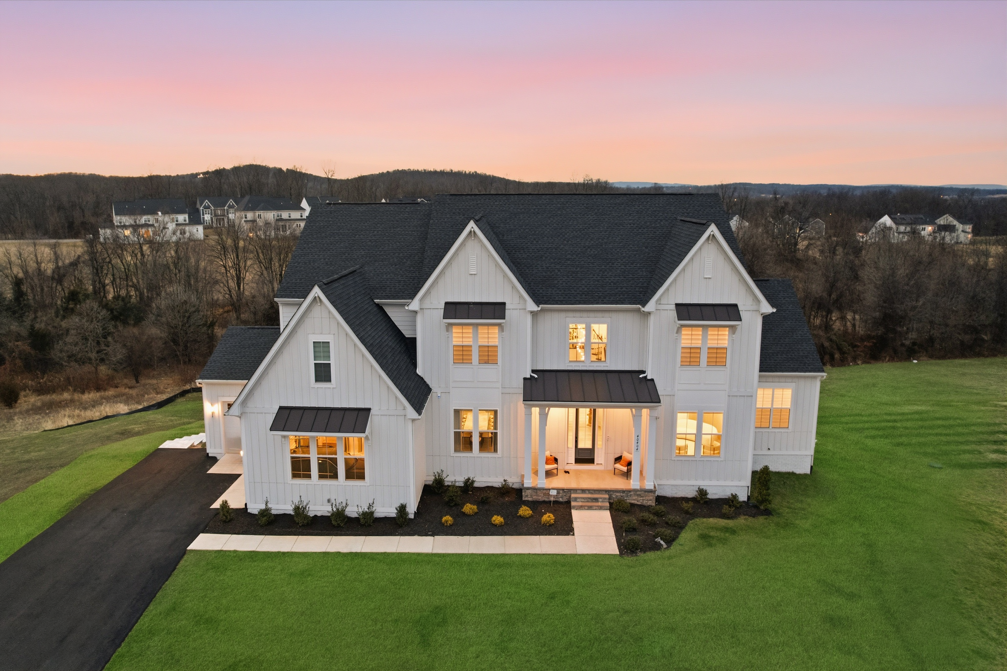 Luxury home exterior photographed at twilight with warm interior lights glowing